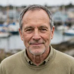 Portrait of Everett Boudreau, WellAheadLife travel contributor, with short grey hair, a light beard and a calm smile.